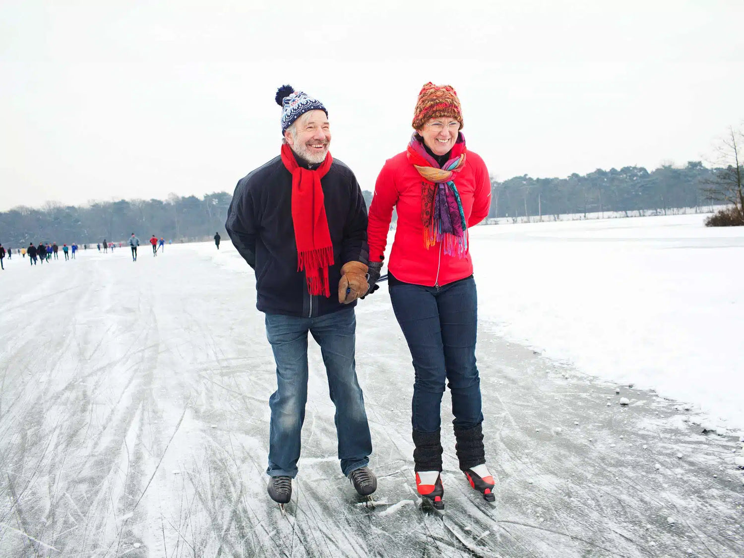 Elternpaar beim Schlittschuhlaufen Hand in Hand über das Eis