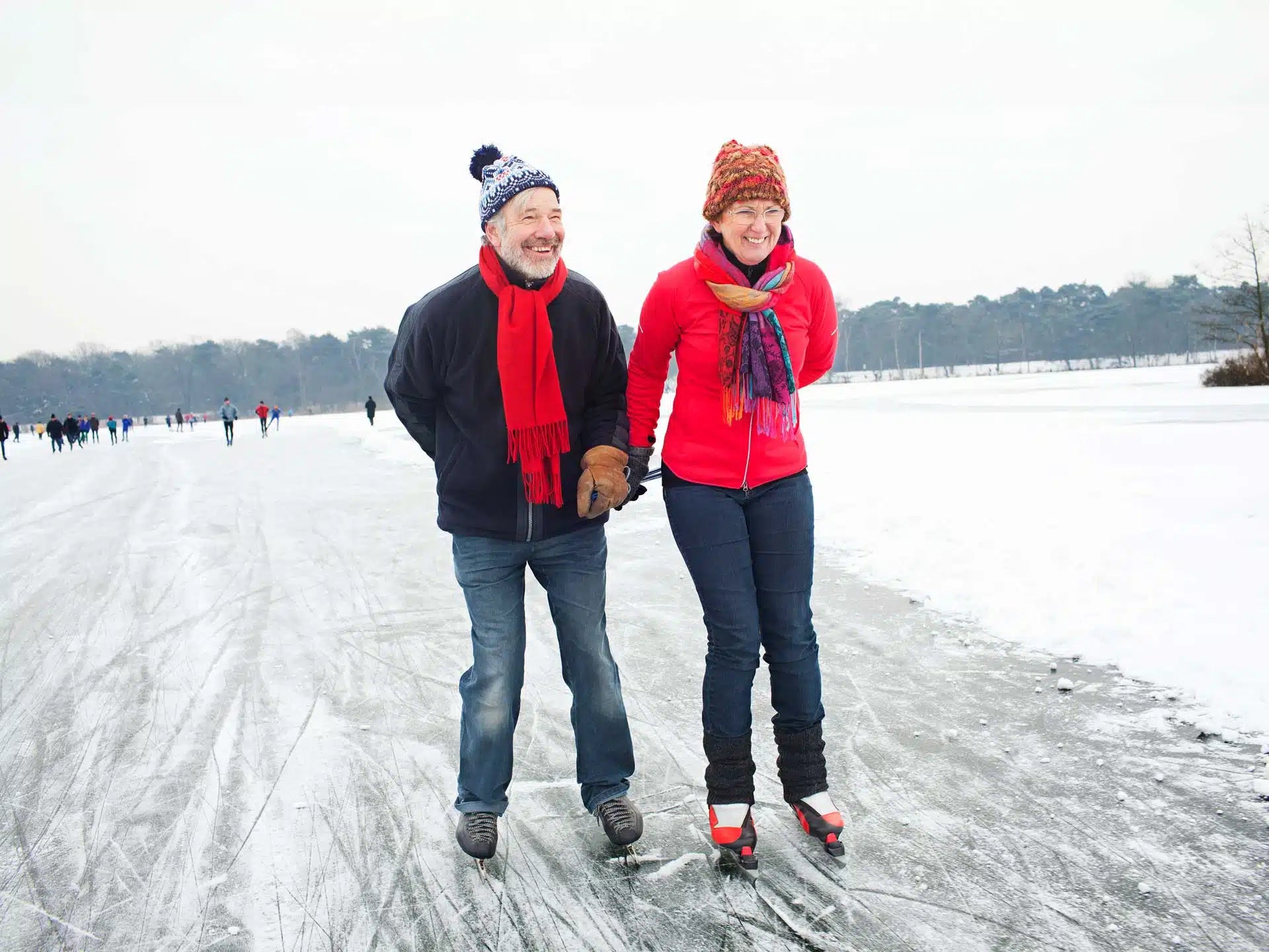 Elternpaar beim Schlittschuhlaufen Hand in Hand über das Eis